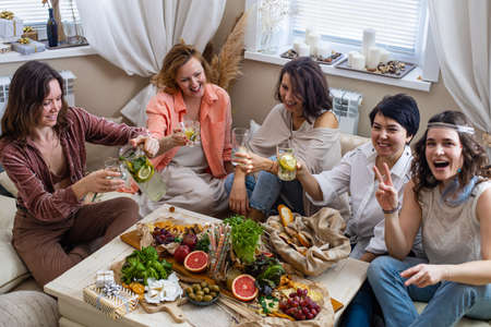 Top view group of happy woman friends posing together at hen-party with healthy food and drink