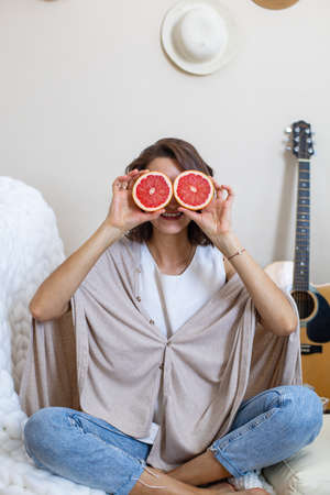 Funny vegan woman posing with half of fresh grapefruit laughing enjoying healthy lifestyle