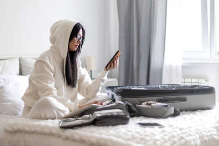 Pensive Asian woman making list of clothes and accessories going to summer travel vacation