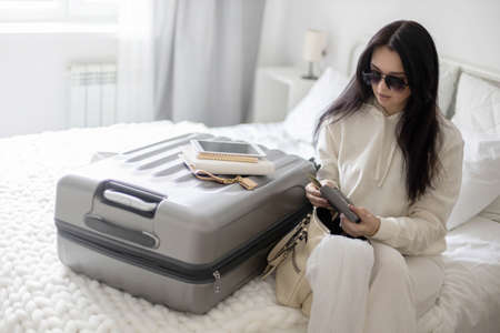 Trendy woman counting checking money cash dollar in wallet before leaving bedroom ready to travelの写真素材