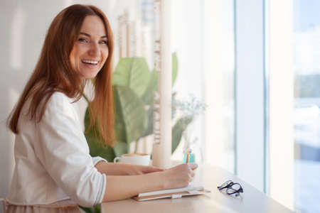 Young businesswoman in eyeglasses planning and writing down the daily schedule with in agendaの写真素材