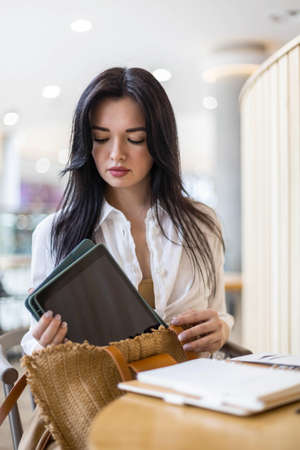Business woman packing tablet, cosmetics, documents into handbagの写真素材