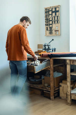 Male tanner working with handpress device machine cutting pattern on stuff material leather workshopの写真素材