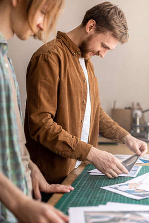 Male professional tanner looking pictures paper photos work examples of handmade leather craft