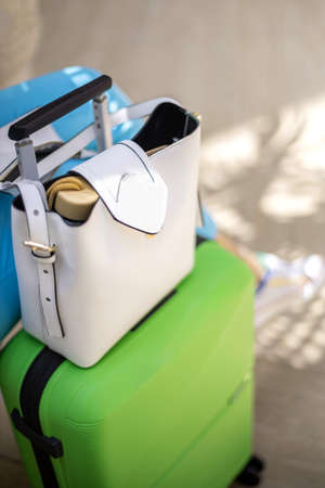 Female bright travel baggage with green suitcase and white handbag at international airport terminalの写真素材