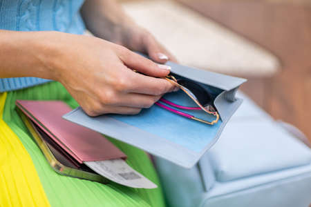 Closeup hands travel woman packing trendy sunglasses into blue storage case box get ready departureの写真素材