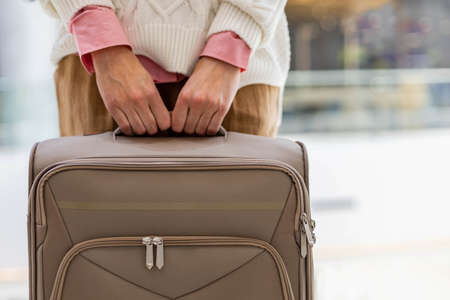 Unrecognizable female passenger holding suitcase posing at duty free international airport terminalの写真素材