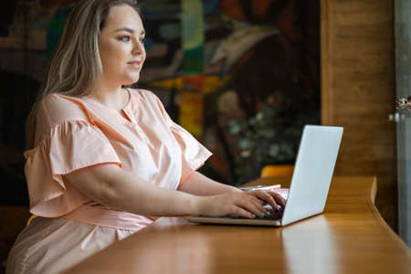 Happy plus size business woman working at cafe use laptop chatting surfing internet