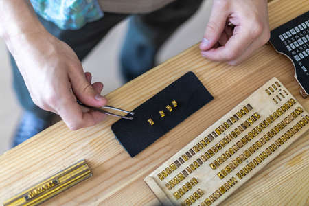 Closeup craftsman hands typing text for branding leather with personal stamp. Creating craft labelの写真素材