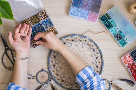 Artistic female hands use colorful beads for creating native tribal Indian amulet dreamcatcherの写真素材