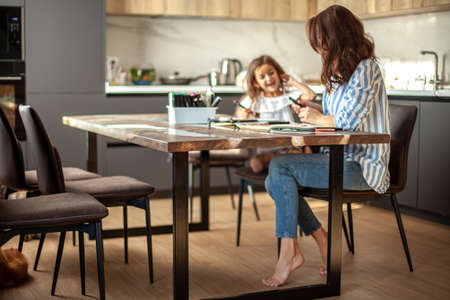 Young beautiful mother and cute daughter draw a mandala pattern together. Artistic markers and colored pencils.の写真素材