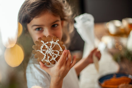 Little cute girl decorates gingerbread with sugar icing. Preparation for Christmas concept.