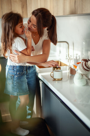A young beautiful mother and a crying daughter are preparing cocoa in a stylish home kitchen.の写真素材