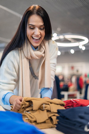 Overjoyed shopaholic woman grabbing clothes at seasonal discount black friday saleの写真素材