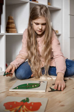 A girl with long hair adds a montessori puzzle to the composition of the plant.の写真素材