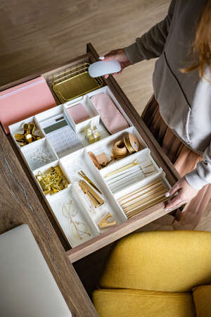 A woman is cleaning up her white workplace. Neatly arranged gold stationery. Storage method.の写真素材