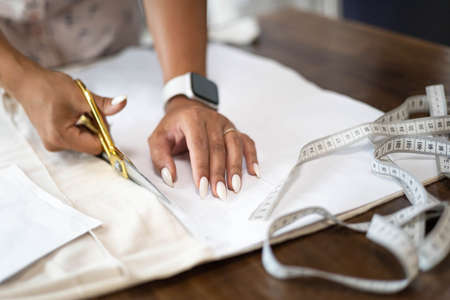 Closeup hands of female professional seamstress cutting textile use scissors making sewing sampleの写真素材