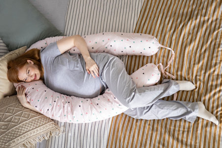 Top view happy future mother lying on comfortable bed hugging pillow for pregnant relaxingの写真素材