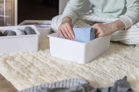Female hands organizing storage of underwear socks t shirts use Marie Kondos method. Perfectionist