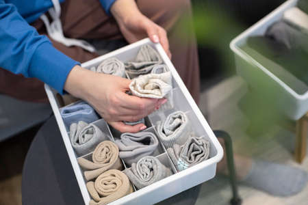 Top view female hands holding organizer drawer divider with socks storage Marie Kondos methodの写真素材
