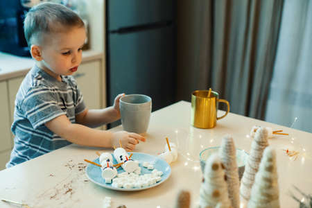 Children make snowmen from marshmallows and salted straws, drink cocoa in the home kitchen. Preparing for Christmas and New Year.の写真素材