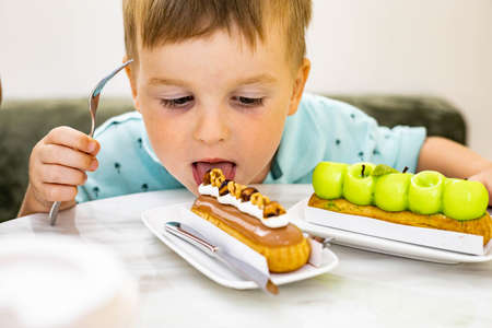 Little boy eating with his mouth without cutlery cake apple eclair