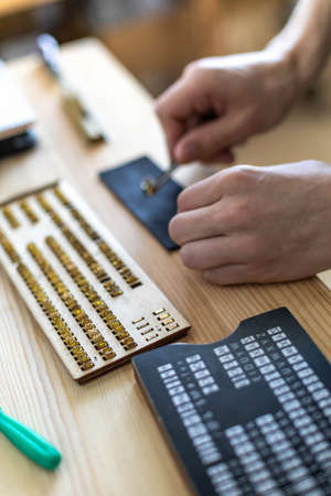 Closeup craftsman hands typing text for branding leather with personal stamp. Creating craft label