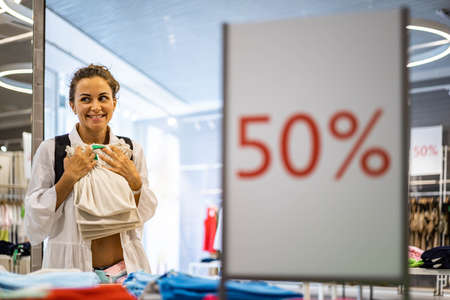Happy woman buyer relaxing enjoying 50 percent sale at fashion boutique choosing clothesの写真素材