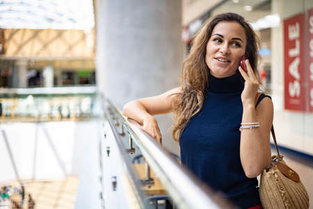 Beautiful fashion female buyer talking use smartphone advising to girlfriend purchasing clothesの写真素材