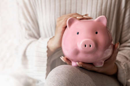 Closeup female hands holding pink piggy bank or money box with savings savings financial cash coinsの写真素材