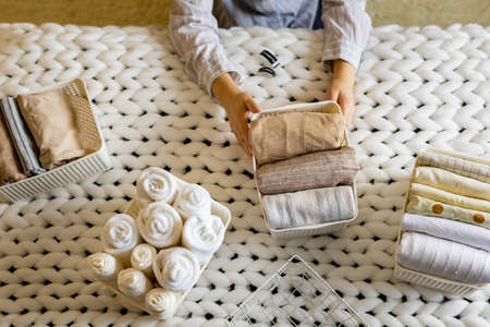 Woman hands neatly folded linens and towels use Marie Kondo method with sticky label tagsの写真素材