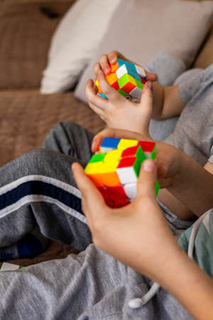 Closeup hands smart babies assembling Rubiks cube 3x3 enjoying early development game at homeのeditorial素材