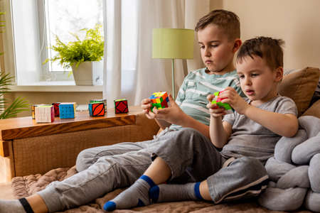 Two male kids brothers assembling Rubiks cube thinking solving logic decisionのeditorial素材