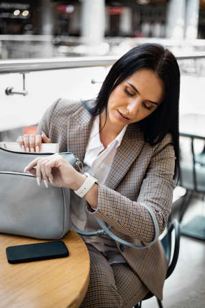 Focused young plus size business woman chatting use mobile phone sitting at table in office interiorの写真素材