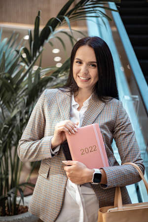 Inspired young Business woman with a smile and holding coral colored diary 2022