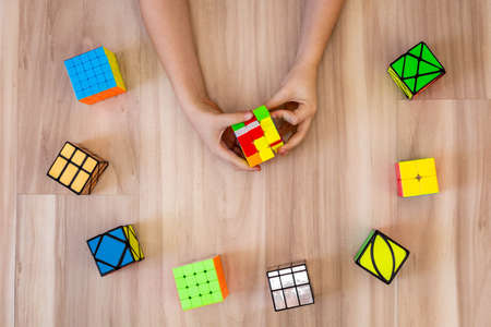 Top view male adolescent hands assembling Rubiks cubes 3x3, axis, 2x2, 4x4, skyube, mirror millのeditorial素材