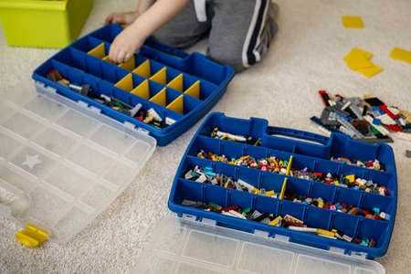 Khabarovsk, Russia, February 18, 2022. Boy sorting Lego colored pieces into boxes with small cells
