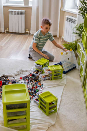 Khabarovsk, Russia, February 18, 2022. Teenager male sorting heap of small Lego pieces into boxesのeditorial素材