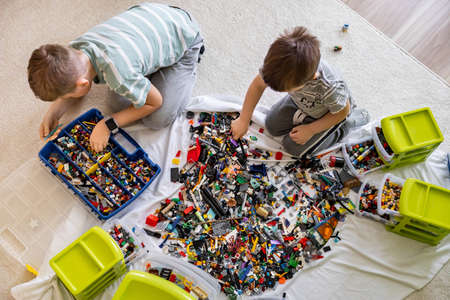 Khabarovsk, Russia, February 18, 2022. Male kids sorting multicolored Lego details into boxesのeditorial素材