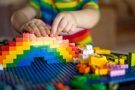 Khabarovsk, Russia, February 25, 2022. Closeup baby boy hands building rainbow use Lego Classicのeditorial素材