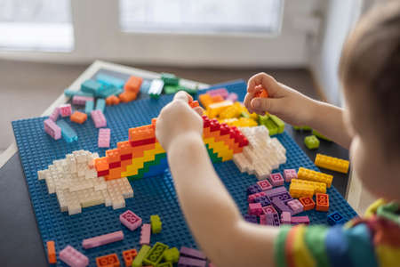 Khabarovsk, Russia, February 25, 2022. Closeup baby boy hands building rainbow use Lego Classicのeditorial素材