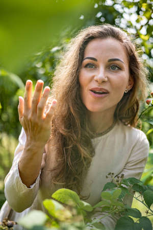 Portrait of Young beautiful girl picks blackberries and raspberries in the garden