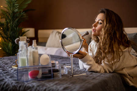 Modern young fashion woman applying beauty products on face use brush and mirrorの写真素材