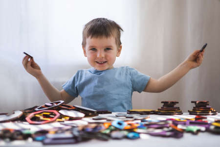 Attentive cute baby boy learning geometric figure shapes playing multicolored wooden constructionの写真素材