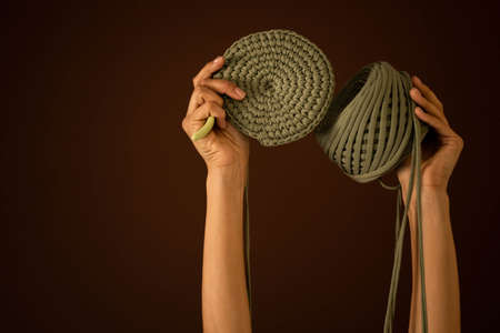 Closeup female hands holding hank of green ribbon yarn and knitting decor or clothes isolated