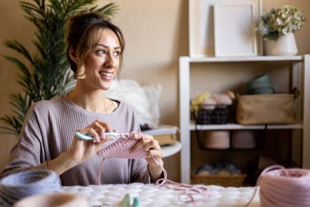 Portrait smiling woman designer knitting clothes and accessories use ribbon yarn and crochet needles