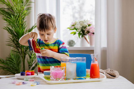 Cute baby boy learning mixing different colors with water and paint in containers. Early developmentの写真素材