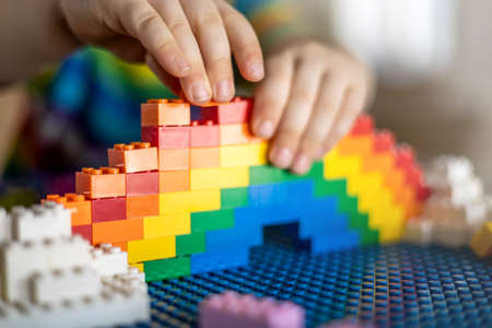 Khabarovsk, Russia, February 25, 2022. Closeup baby boy hands building rainbow use Lego Classicのeditorial素材