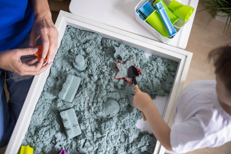 Cute male kid son and mother playing kinetic sand form early development educational game top viewの写真素材