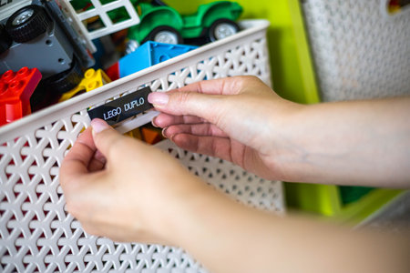 Mother hands sticking label sticker with name title of toy for comfortable storage and sorting